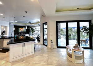 Kitchen featuring a raised ceiling, open floor plan, white cabinets, dishwasher, and dark stone countertops