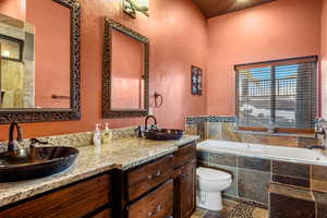 Full bath with a bath, a textured wall, and double vanity