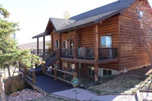 View of side of home with a deck, stairs, and a shingled roof