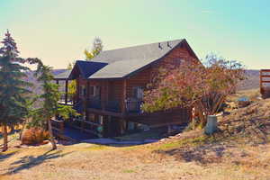 Back of property at dusk with a wooden deck and roof with shingles