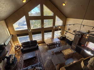 Living area with high vaulted ceiling and hardwood / wood-style floors