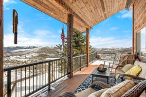 Snow covered back of property featuring an outdoor living space, a mountain view, and a patio area