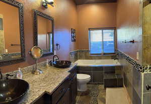 Full bathroom featuring double vanity, a garden tub, and a textured wall