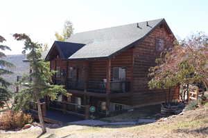 Back of house with a wooden deck and a shingled roof