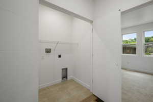 Laundry area featuring hookup for a washing machine, electric dryer hookup, light tile patterned floors, and light colored carpet