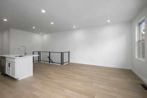 Kitchen featuring an island with sink, recessed lighting, light wood-style flooring, stainless steel dishwasher, and white cabinets