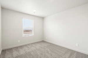 Carpeted spare room with baseboards