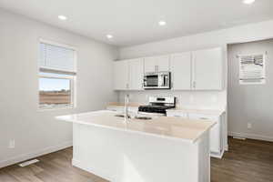 **DISCLAIMER- exterior and interior options will vary**Kitchen featuring a kitchen island with sink, white cabinetry, appliances with stainless steel finishes, recessed lighting, and light stone countertops