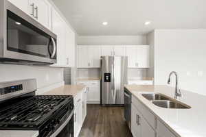 **DISCLAIMER- exterior and interior options will vary**Kitchen with appliances with stainless steel finishes, white cabinetry, dark wood-style floors, light stone counters, and recessed lighting