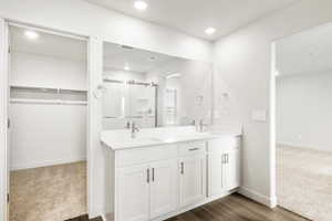 Bathroom featuring a spacious closet, double vanity, a shower stall, dark colored carpet, and recessed lighting