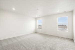 Empty room featuring healthy amount of natural light, light carpet, and recessed lighting