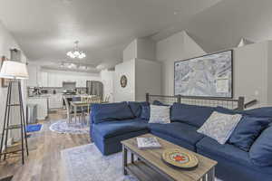 Living area featuring lofted ceiling, track lighting, light wood-style floors, and a chandelier