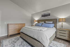 Bedroom featuring wood finished floors and vaulted ceiling