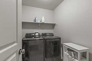 Laundry area featuring washing machine and dryer, wood finished floors, and a textured ceiling
