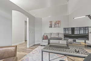 Living area with arched walkways and light wood-style floors