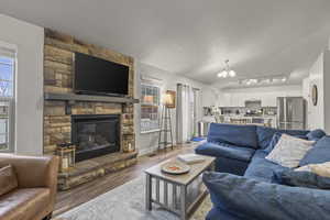 Living area with wood finished floors, a fireplace, and a chandelier