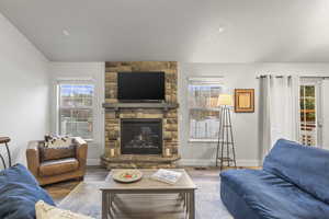 Living room featuring wood finished floors, a stone fireplace, and plenty of natural light
