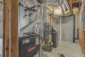 Utility room featuring secured water heater and heating unit