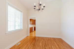 Unfurnished dining area featuring light wood-style floors and a chandelier