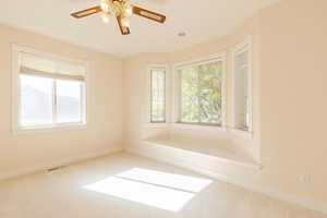 Unfurnished room featuring healthy amount of natural light, carpet flooring, and a ceiling fan