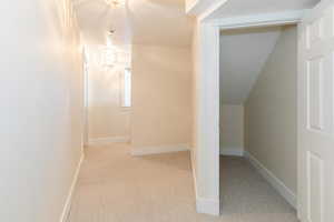 Bonus room featuring a textured ceiling, light colored carpet, and vaulted ceiling