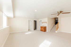 Unfurnished living room with light colored carpet, stairs, ceiling fan, a textured ceiling, and recessed lighting
