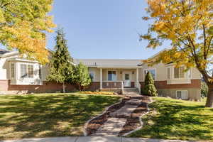 View of front of property featuring brick siding, a front lawn, and covered porch
