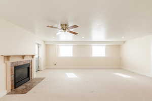 Unfurnished living room with light colored carpet, a tile fireplace, ceiling fan, a textured ceiling, and recessed lighting