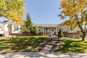 Single story home with brick siding, a front yard, and a porch