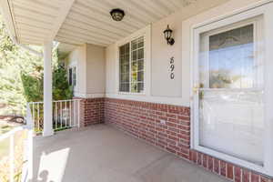 Property entrance with a porch, brick siding, and stucco siding