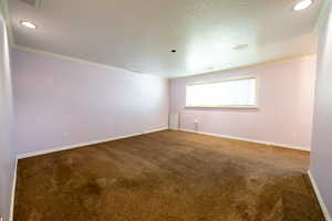 Unfurnished primary bedroom with dark carpet, ornamental molding, a textured ceiling, and recessed lighting