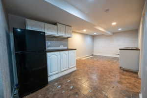 Kitchen with freestanding refrigerator, dark countertops, white cabinets, backsplash, and recessed lighting