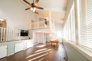 Unfurnished living room featuring hardwood / wood-style floors, ceiling fan, stairway, high vaulted ceiling, and pool table