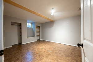 Unfurnished bedroom with baseboards and beam ceiling