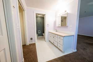 Bathroom featuring crown molding, light carpet, and vanity