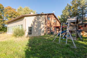 Back of property featuring a playground and a lawn