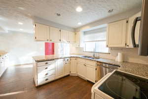 Kitchen featuring electric stove, a textured ceiling, light stone counters, dishwasher, and recessed lighting