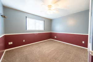 Carpeted empty room featuring baseboards and a ceiling fan