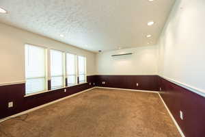 Empty room featuring recessed lighting, a textured ceiling, carpet flooring, and a wainscoted wall