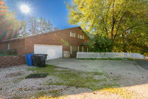 View of home's exterior with a garage, a fenced front yard, concrete driveway, and brick siding