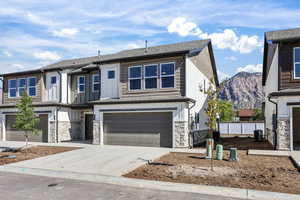 View of front of house with stone siding, driveway, an attached garage, a mountain view, and board and batten siding