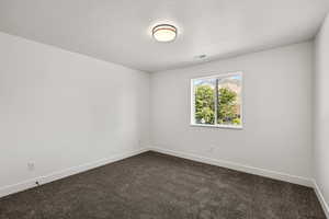 Spare room with dark carpet and a textured ceiling