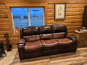 Living area featuring rustic walls, a wood stove, and wood finished floors