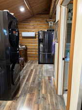 Kitchen featuring wood finished floors, fridge with ice dispenser, wooden ceiling, black refrigerator, and log walls