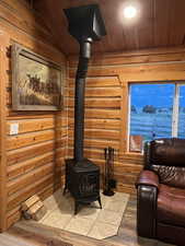 Living area with a wood stove, wooden ceiling, and wood finished floors