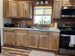 Kitchen with stainless steel appliances, dark wood-type flooring, and brown cabinetry
