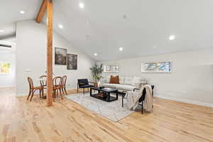 Living area with beamed ceiling, recessed lighting, light wood-style floors, and high vaulted ceiling