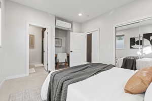 Carpeted bedroom featuring ensuite bathroom, a closet, recessed lighting, and an AC wall unit