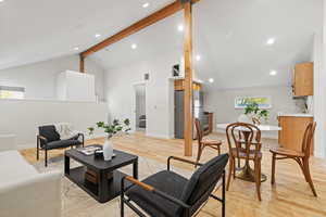 Living area with beam ceiling, light wood-style flooring, recessed lighting, and high vaulted ceiling