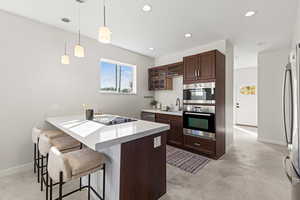Kitchen with a peninsula, a kitchen bar, glass insert cabinets, dark brown cabinetry, and hanging light fixtures